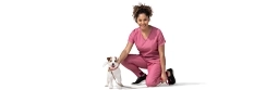 A female vet kneels next to a dog.